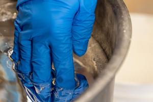 Erik Gilson, head of PPPL’s discovery plasma science, puts his fingers into a vat of liquid metal.