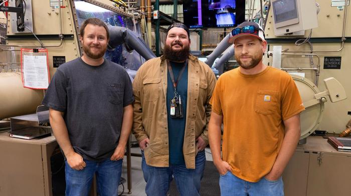 (Left to right) Michael Cornell, Kyan Voronovich and Roger Williams posing in front of welding gloveboxes. Not pictured: Blake Dixon