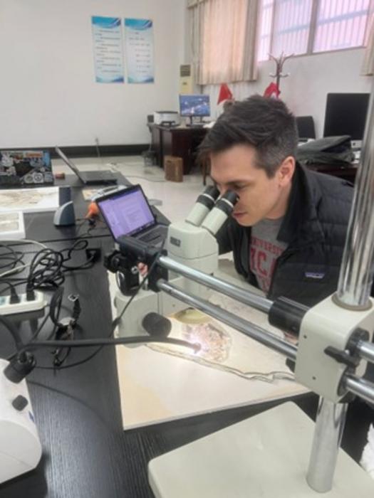 Alexander Clark, assessing the Plumadraco fossil under a microscope.