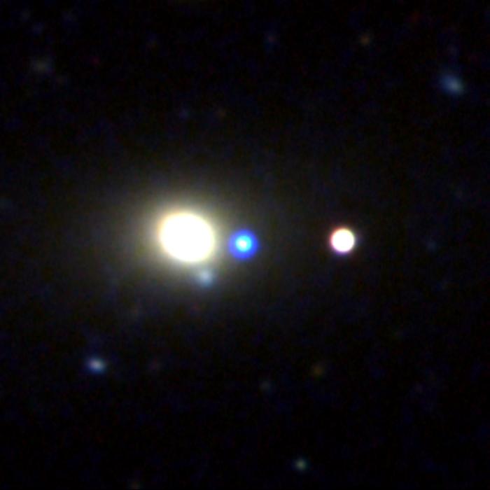 A supermassive black hole revealed itself with a flash of light, shown at the center of this image in blue, as it wandered the edge of a galaxy.