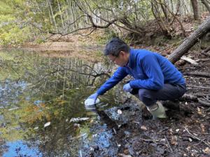 Minamoto collects water from a pond for use in environmental DNA surveys
