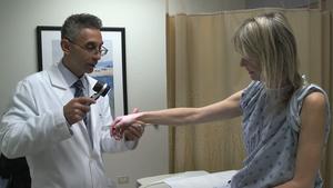Dr. Pedram Gerami examines the skin of patient and melanoma survivor Heidi Tarr